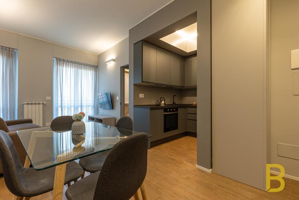 uma sala de jantar e sala de estar com uma mesa de vidro e cadeiras em BePlace Apartments in Primaticcio em Milão