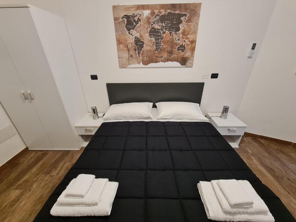 アルゲーロにあるMonti Guest House Algheroのベッドルーム1室(黒いベッド1台、白いタオル2枚付)