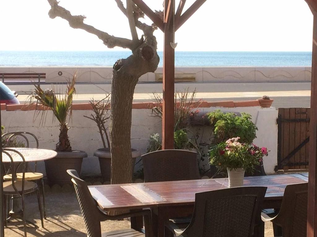 une table et des chaises avec vue sur la plage dans l'établissement Villa en front de mer, à Narbonne-Plage