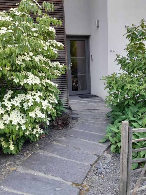 uma passagem que leva a uma casa com flores brancas em meublé de tourisme à Bouillon em Bouillon