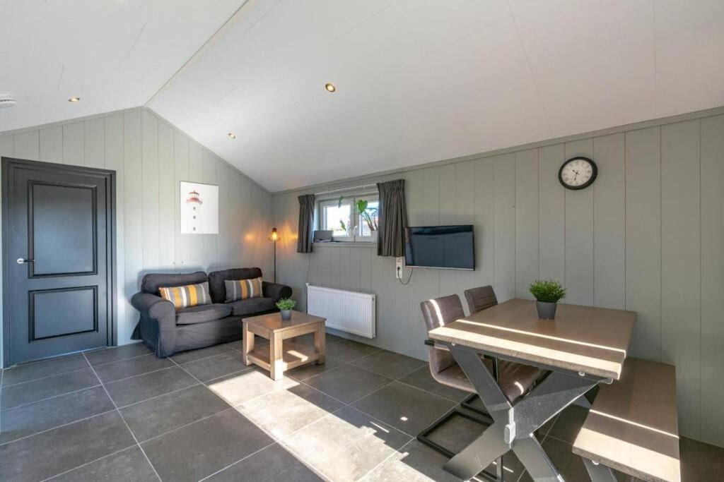 een woonkamer met een bank en een tafel bij NEW! Strandhuis 't Koepeltje aan zee! in Callantsoog