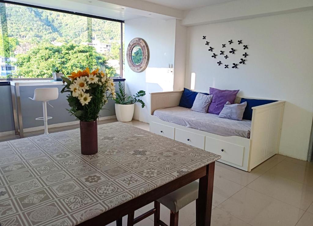 una habitación con sofá y mesa con un jarrón de flores en The Warren @Torreavila en Caracas