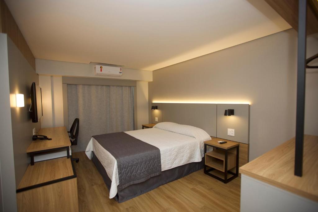 a hotel room with a bed and a desk at Mogano Business Hotel- ELETROPOSTO in Chapecó
