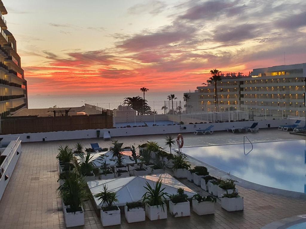 a view of a hotel with a pool and a sunset at Royal Park Torviscas Beach in Adeje