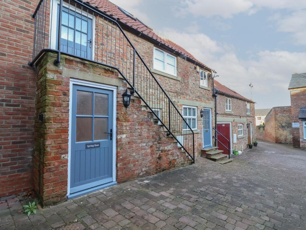 a brick house with a blue door and stairs at Spring Rose in Bedale