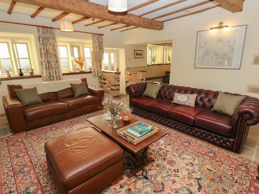 sala de estar con sofás de cuero y mesa de centro en The Farmhouse en Keighley
