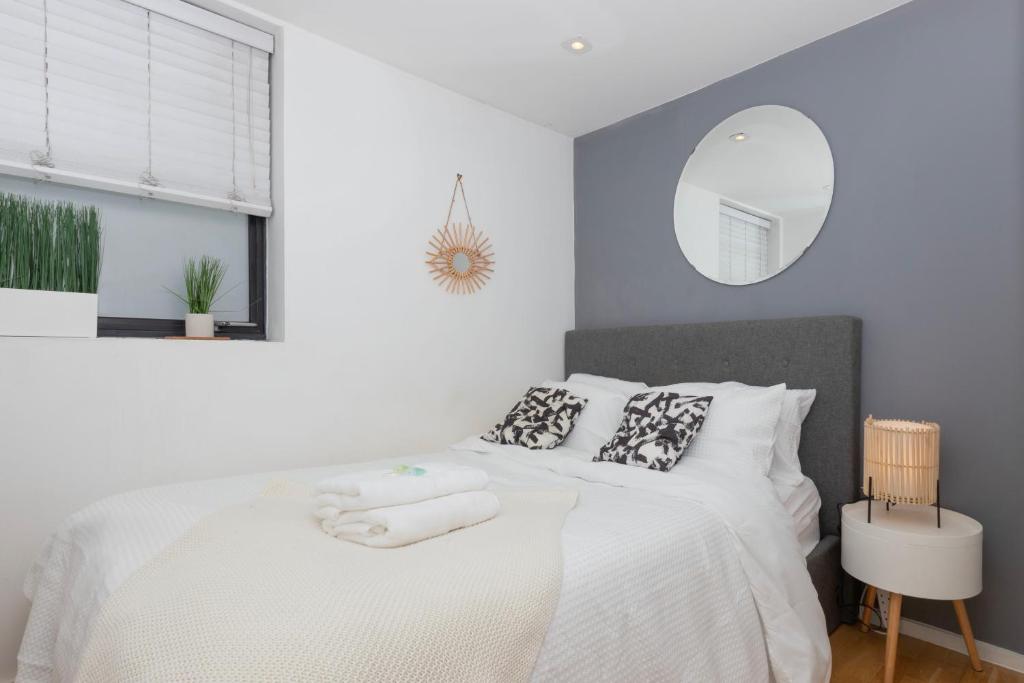 a bedroom with a white bed and a mirror at Cosy Ground Floor Apartment in London