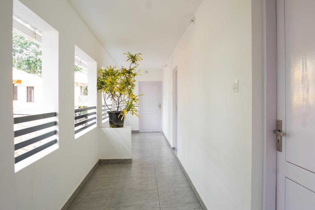 un pasillo con paredes blancas y una puerta con una maceta en Avanthi Homestay en Varkala