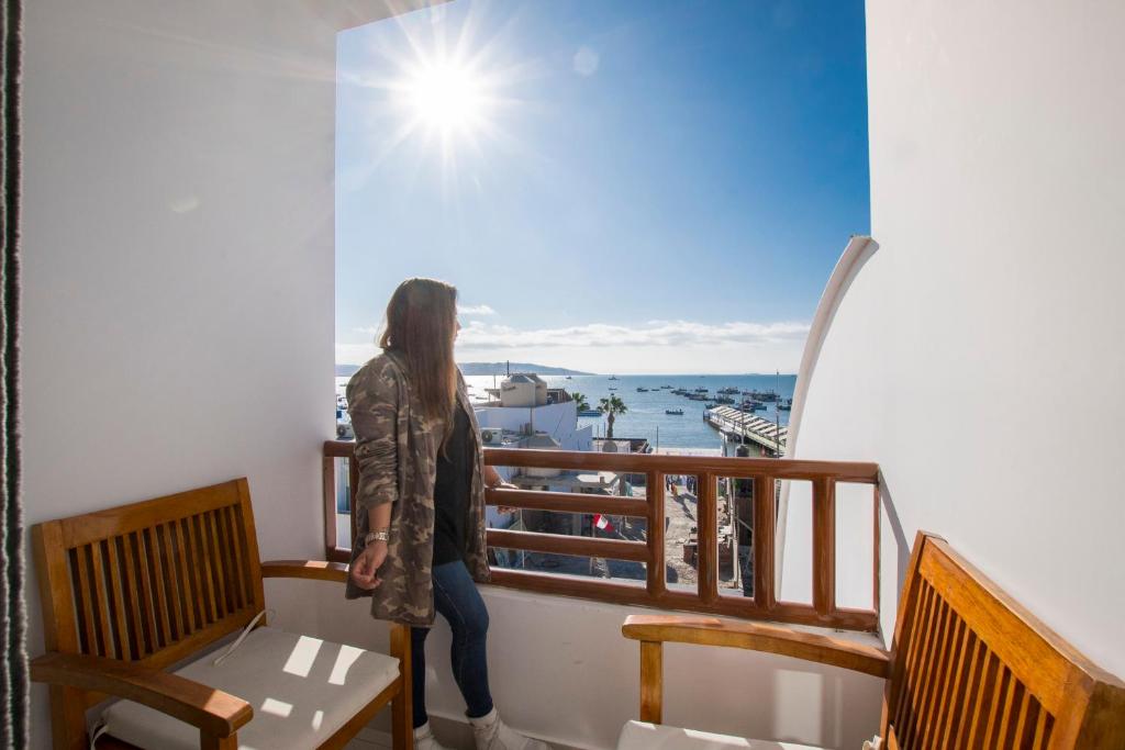 Una mujer parada en un balcón con vistas al agua en Hotel Riviera Inka Paracas, en Paracas