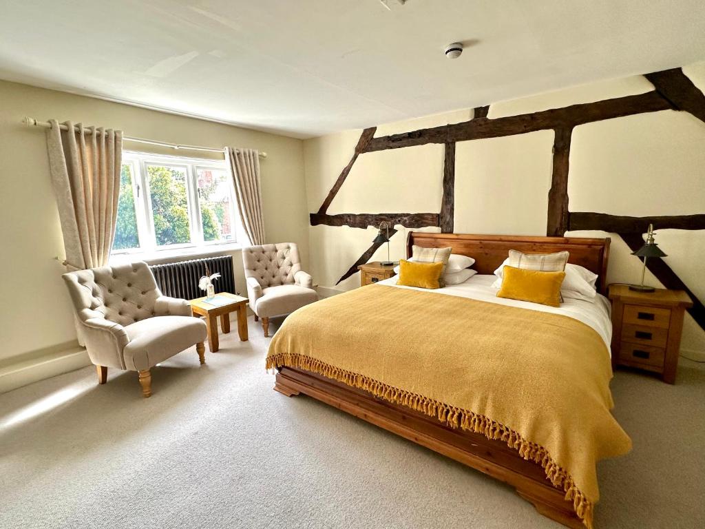 a bedroom with a large bed and two chairs at The Manor at Abberley in Abberley