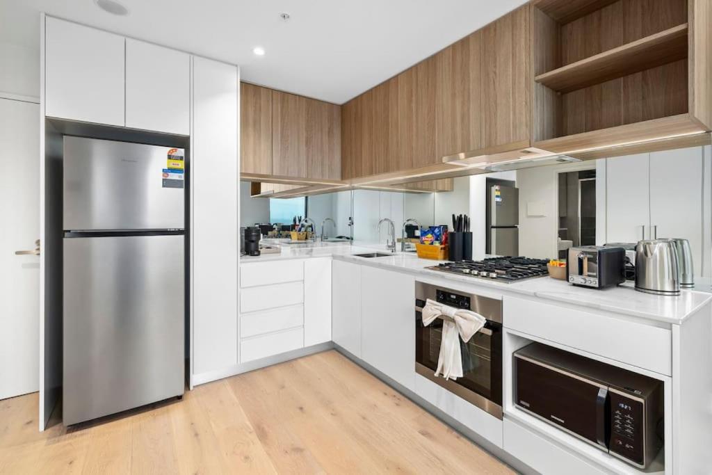 een keuken met witte kasten en roestvrijstalen apparatuur bij Stunning Stature Southbank 2bed in Melbourne
