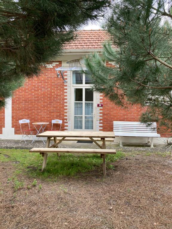 a wooden picnic table in front of a brick building at La Rosaire in Soulac-sur-Mer