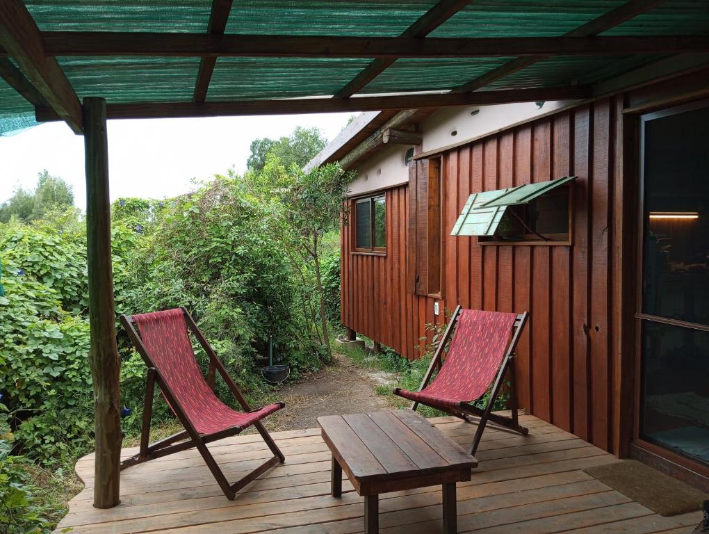 2 sillas y una mesa en una terraza de madera en Sietevestidos Casa Ecológica - Punta Negra, en Punta Colorada
