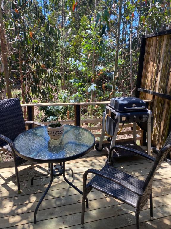 un patio con mesa, 2 sillas y parrilla en Refugio Nomade Apartamentos, en Pichilemu