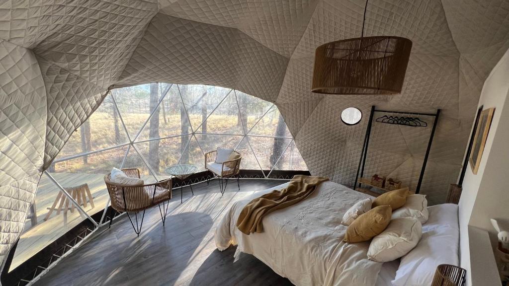 - une chambre avec un lit dans une pièce dotée d'une grande fenêtre dans l'établissement Deer Glamping, à Luján de Cuyo