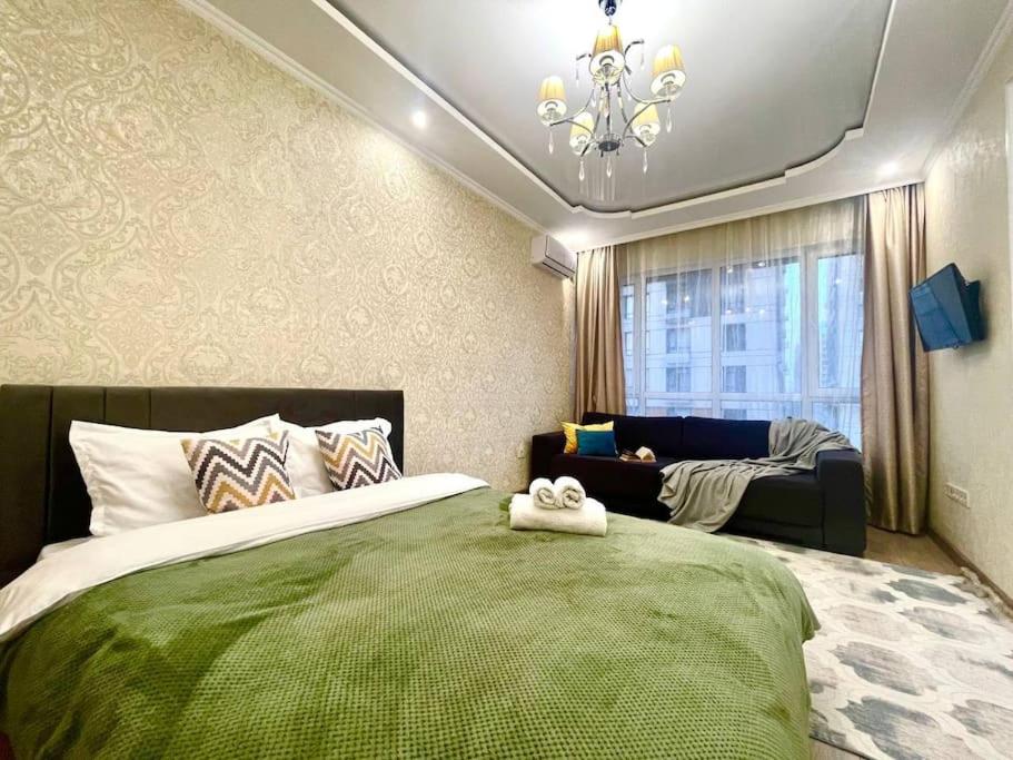 ein Schlafzimmer mit einem grünen Bett und einem Sofa in der Unterkunft Уютная квартира в верхней части города in Almaty
