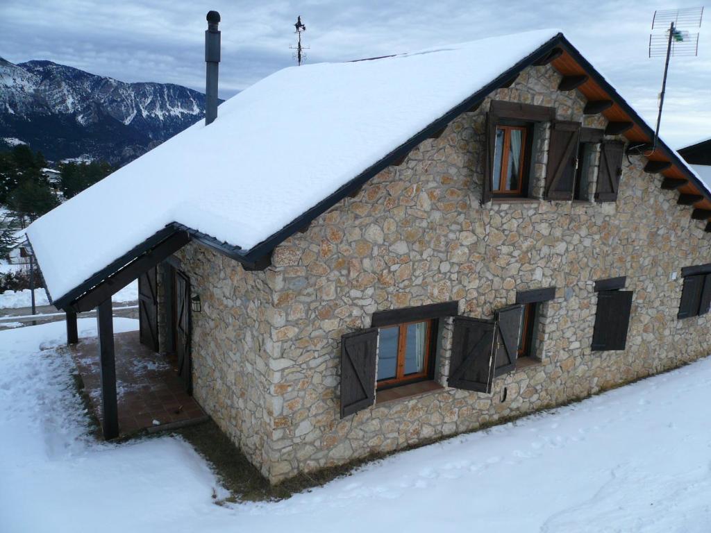ein Steingebäude mit Schnee auf dem Dach in der Unterkunft Port del Comte a pie de pistas in La Coma i la Pedra