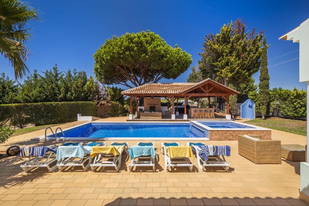 een groep stoelen en een zwembad met een prieel bij Villa Cambria by OCvillas in Albufeira