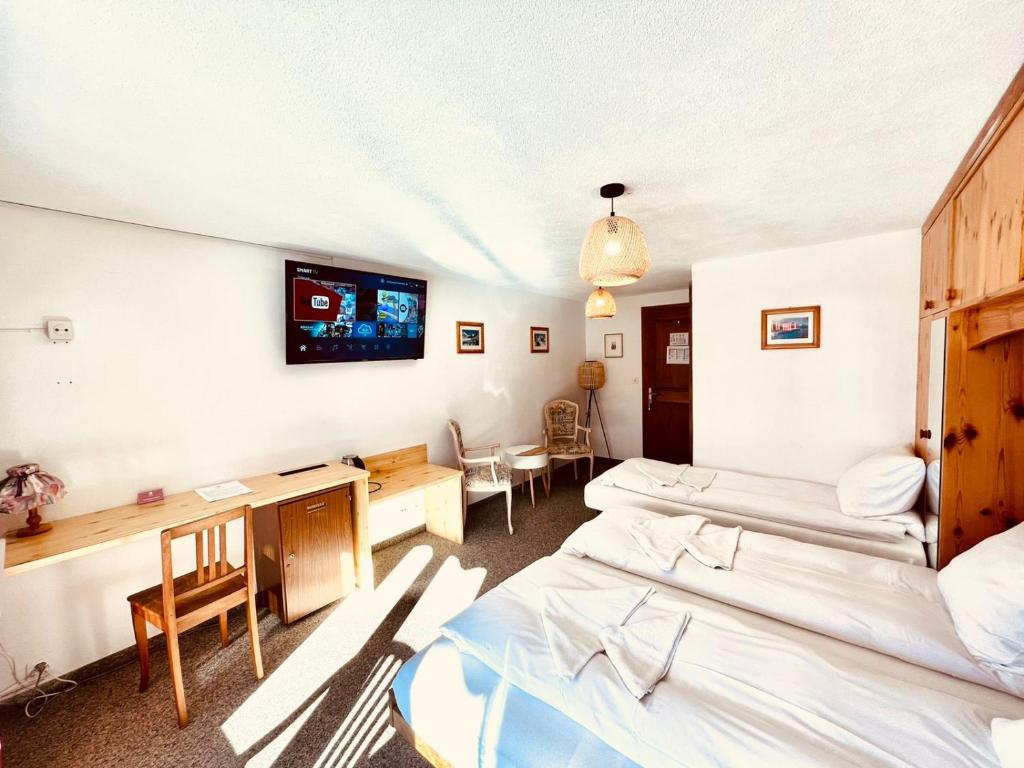 Hotel Old JNN في Klosters Serneus: غرفة بثلاث اسرة ومكتب وتلفزيون