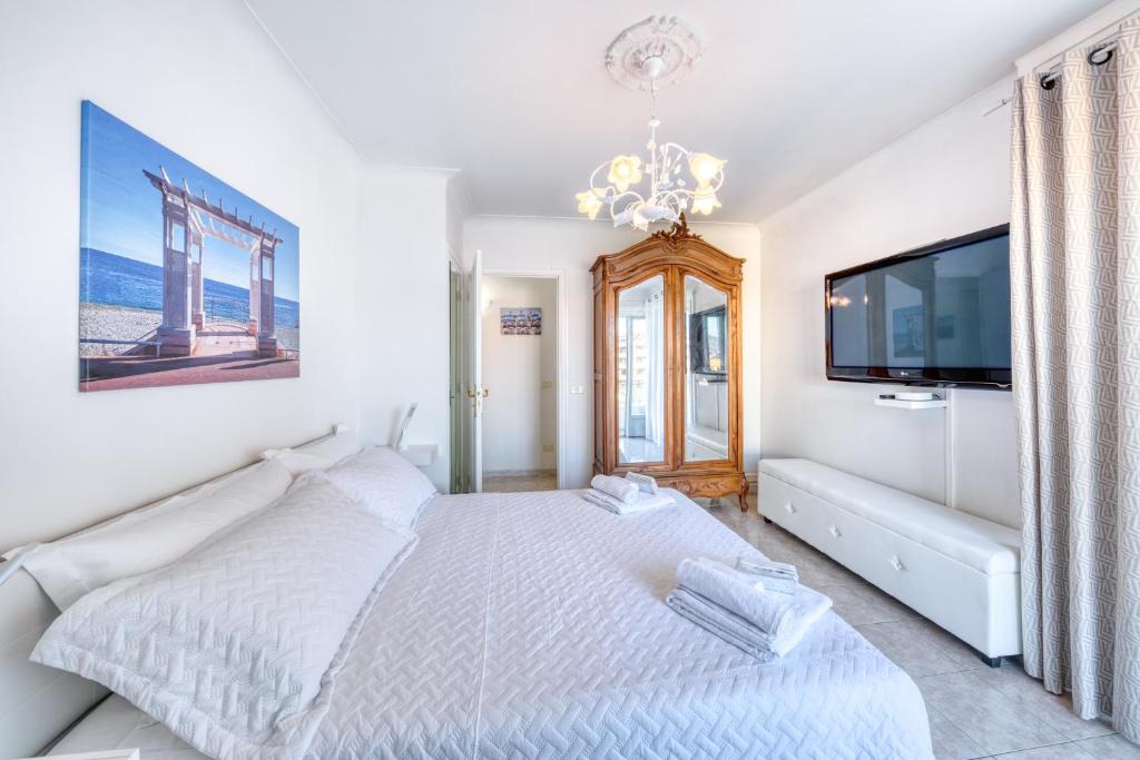 a white bedroom with a bed and a flat screen tv at FAMILY APARTMENT SEA VIEW in Nice