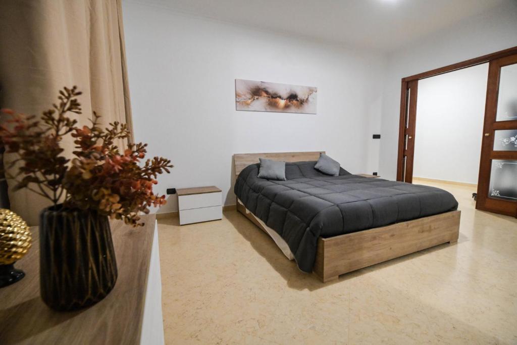 1 dormitorio con 1 cama y un jarrón de flores en Casa di Serena en Barletta