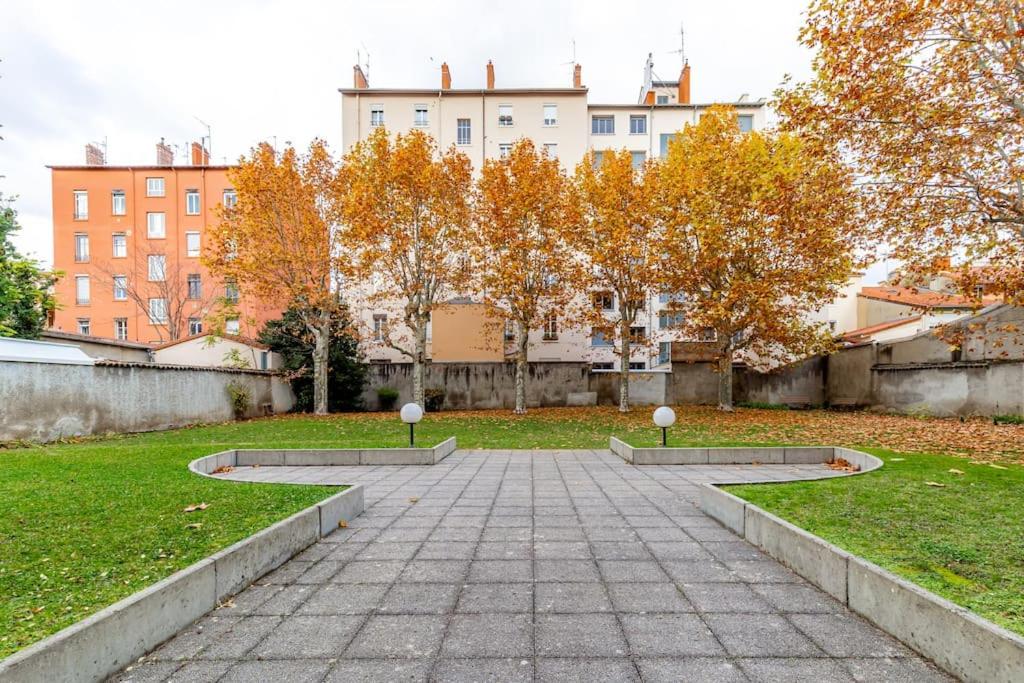 a walkway in a park with trees and buildings at Grand &amp; Lumineux T2 au Coeur de Monplaisir • Métro à 2’ • Parking Privé in Lyon