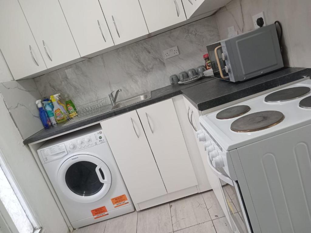 a kitchen with a washing machine and a microwave at Good priced double bed rooms in harrow with shared bathrooms in Hatch End
