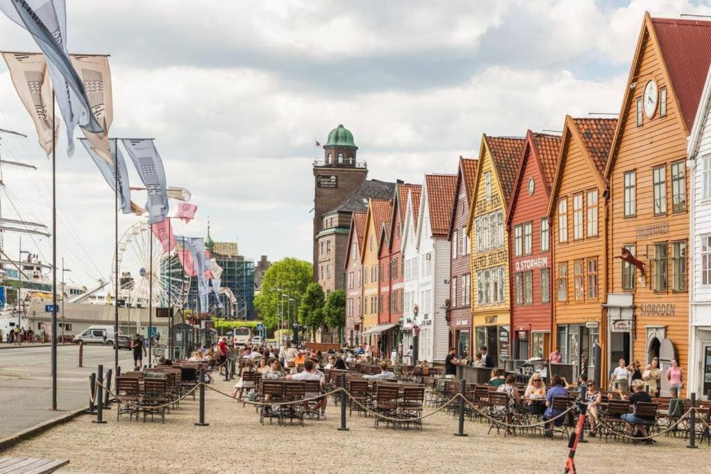 een stadsstraat met gebouwen en mensen aan tafel bij Dinbnb Apartments I The Bryggen Experience I Enjoy Life with Friends & Family in Bergen