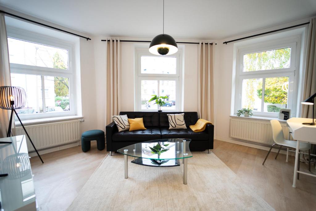 sala de estar con sofá negro y 2 ventanas en Charles & Kätchen living Gohlis, en Leipzig