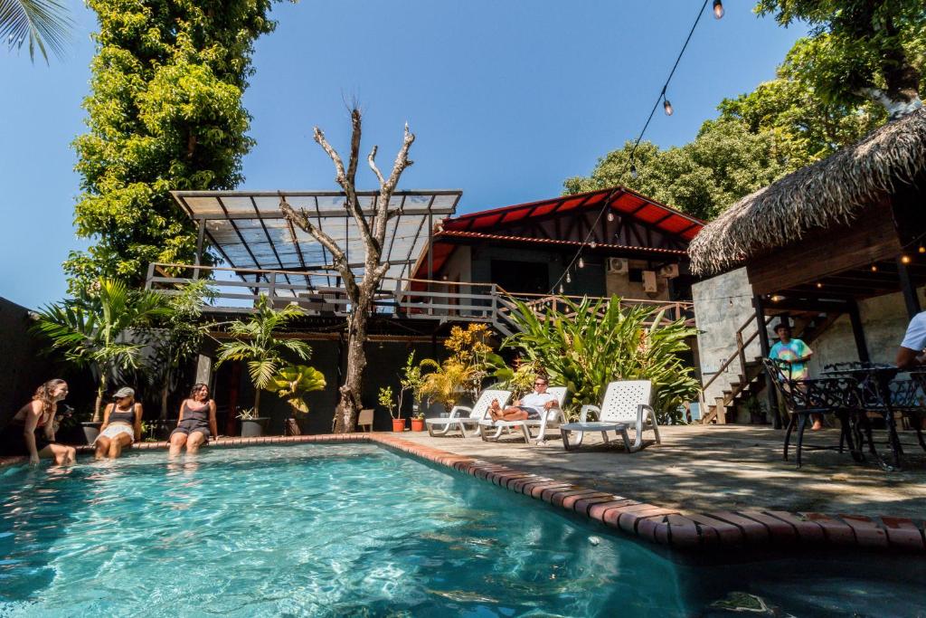 um grupo de pessoas sentadas ao redor de uma piscina em Hostel Villa Vento Surf em Santa Catalina