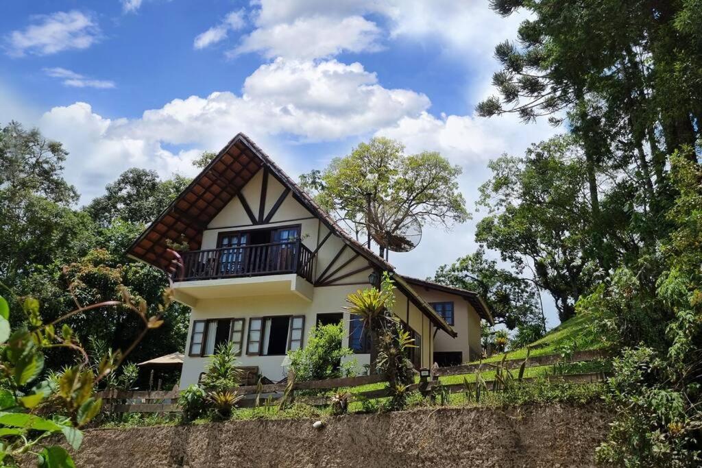 una casa en la cima de una colina con árboles en Chalé Pedra do índio - no coração de Maringá MG, en Bocaina de Minas