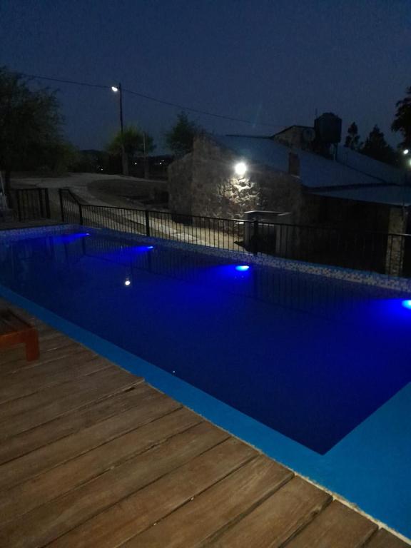 a blue swimming pool at night with a wooden deck at Cabañas Wasirumi Pileta y bajada al Rio in Bialet Massé