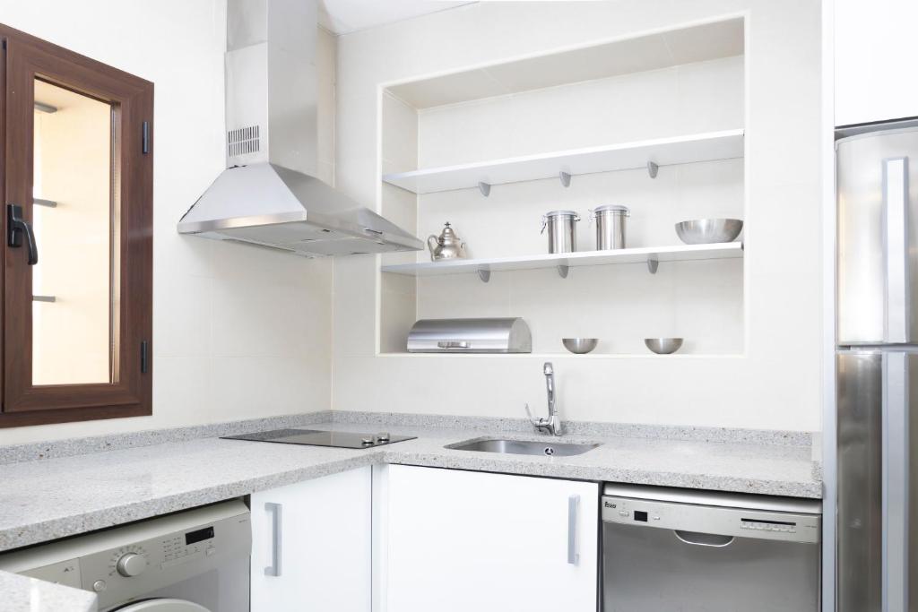 a white kitchen with white cabinets and a sink at Palacio de Luja in El Puerto de Santa María