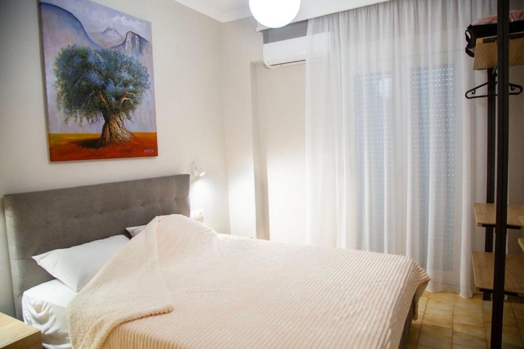 a bedroom with a bed with a tree painting on the wall at Minimal House in Paralia Katerinis