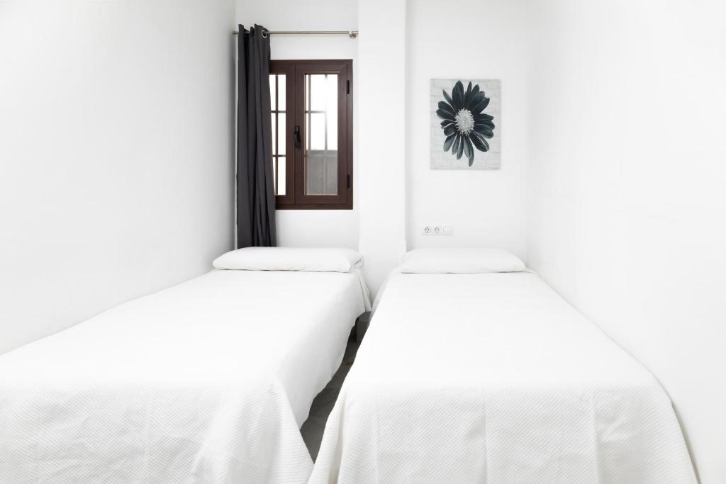 two beds in a room with white walls at Palacio de Luja in El Puerto de Santa María