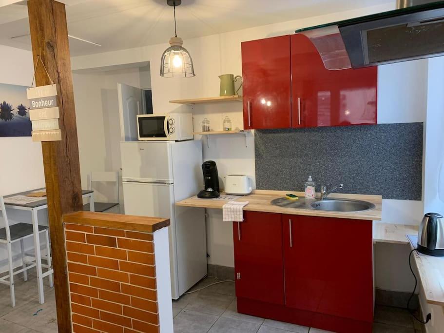 a kitchen with red cabinets and a sink at Appartement avec terrasse 2 in Gien