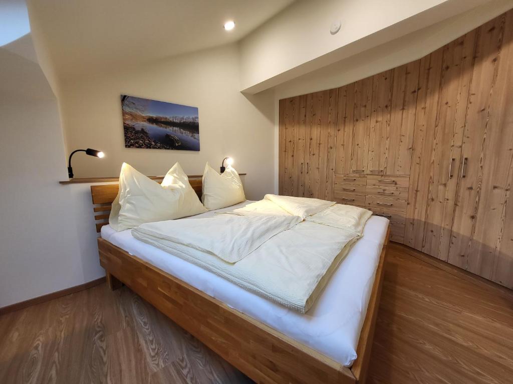 1 dormitorio con 1 cama grande y pared de madera en Appartements MAYR inklusive ganzjährig GRATIS Zugang zur ALPENTHERME und im SOMMER kostenlose Bergbahnnutzung, en Bad Hofgastein