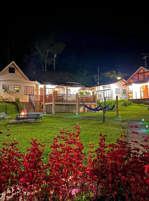 una casa con una hamaca en un patio por la noche en CasaComVida pousada en Santo Antônio do Pinhal