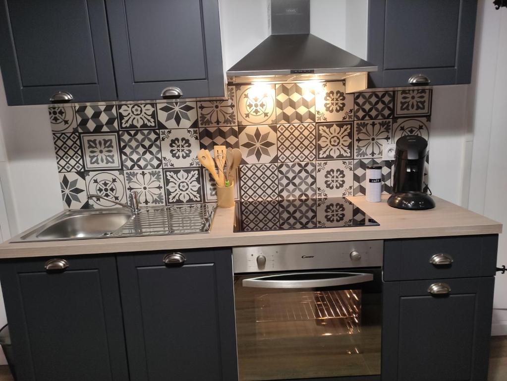 uma cozinha com armários pretos e um lavatório e azulejos em Bienvenue chez Coco em Dunkerque