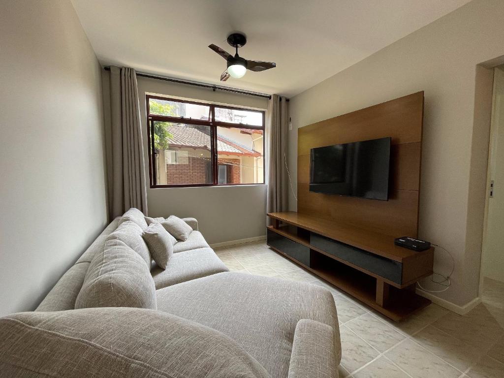 uma sala de estar com um sofá e uma televisão de ecrã plano em Lindo Apartamento em Canasvieiras Perto da Praia em Florianópolis