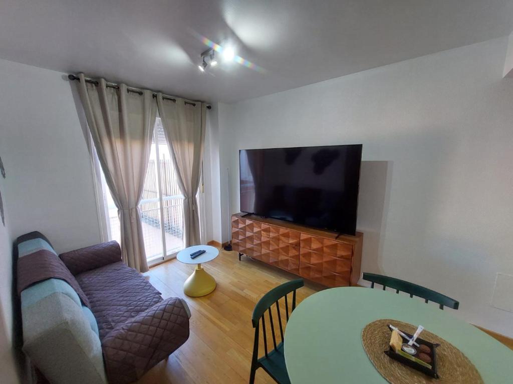 a living room with a couch and a table and a tv at Apartamento CentroLinares Con Parking in Linares