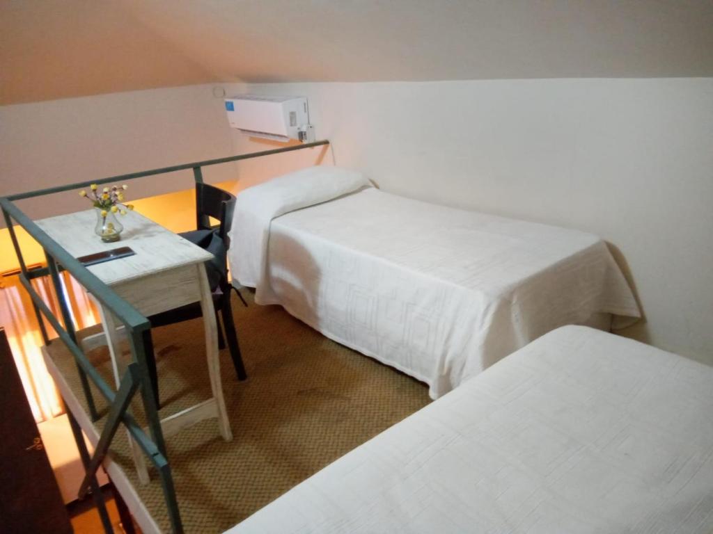 a room with two beds and a table with a desk at Daily Suites Hotel Boutique in Puerto San Julián