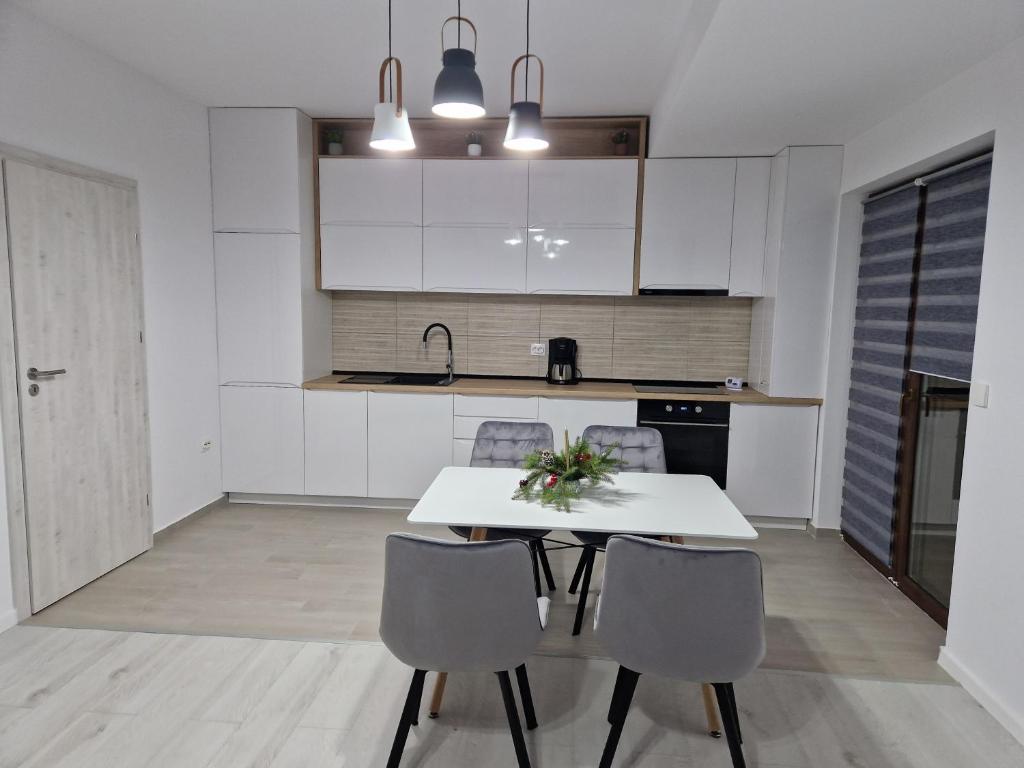 a white kitchen with a white table and chairs at Apartament Eva in Cristian