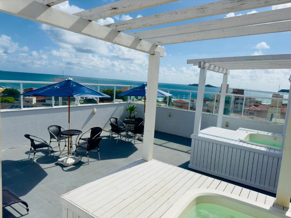 um pátio com uma banheira de hidromassagem, cadeiras e um guarda-sol em Gaivotas Praia Hotel em Florianópolis