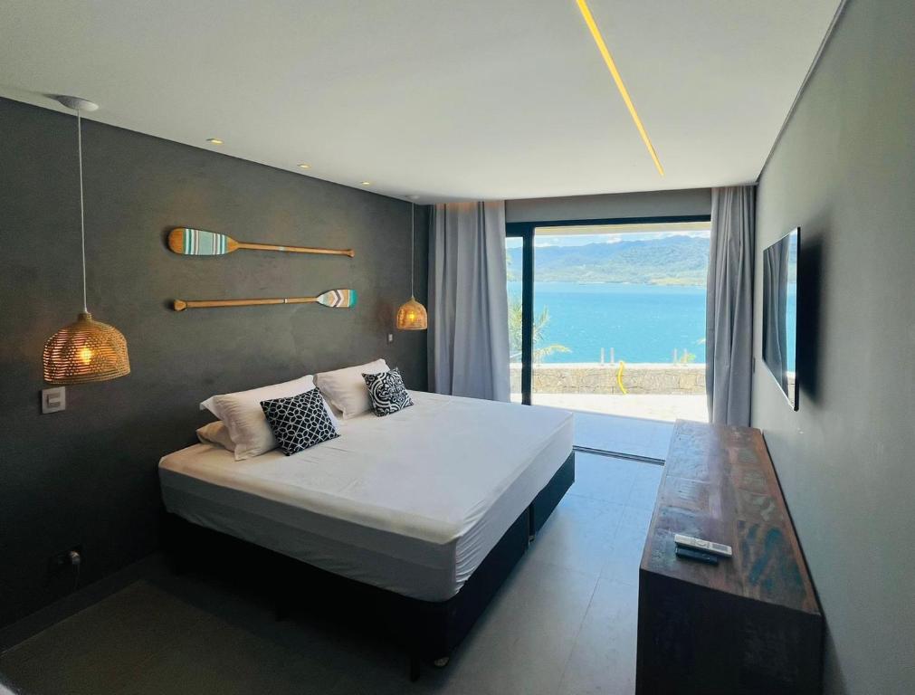 a bedroom with a bed with a view of the ocean at Suites na Casa da Praia in Ilhabela