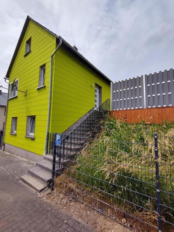 ein gelbes Haus mit einem Zaun davor in der Unterkunft Haus Rosi in Lutzerath