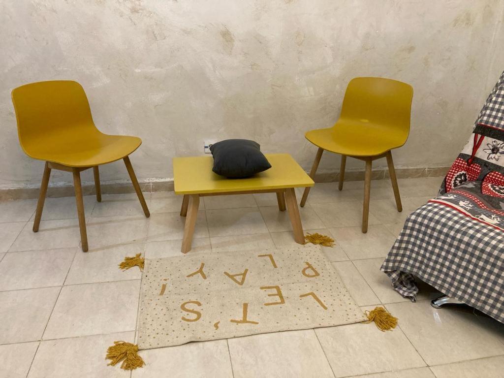 2 gelbe Stühle, ein Tisch und ein Teppich in der Unterkunft Charmante location ensoleillée in Alger
