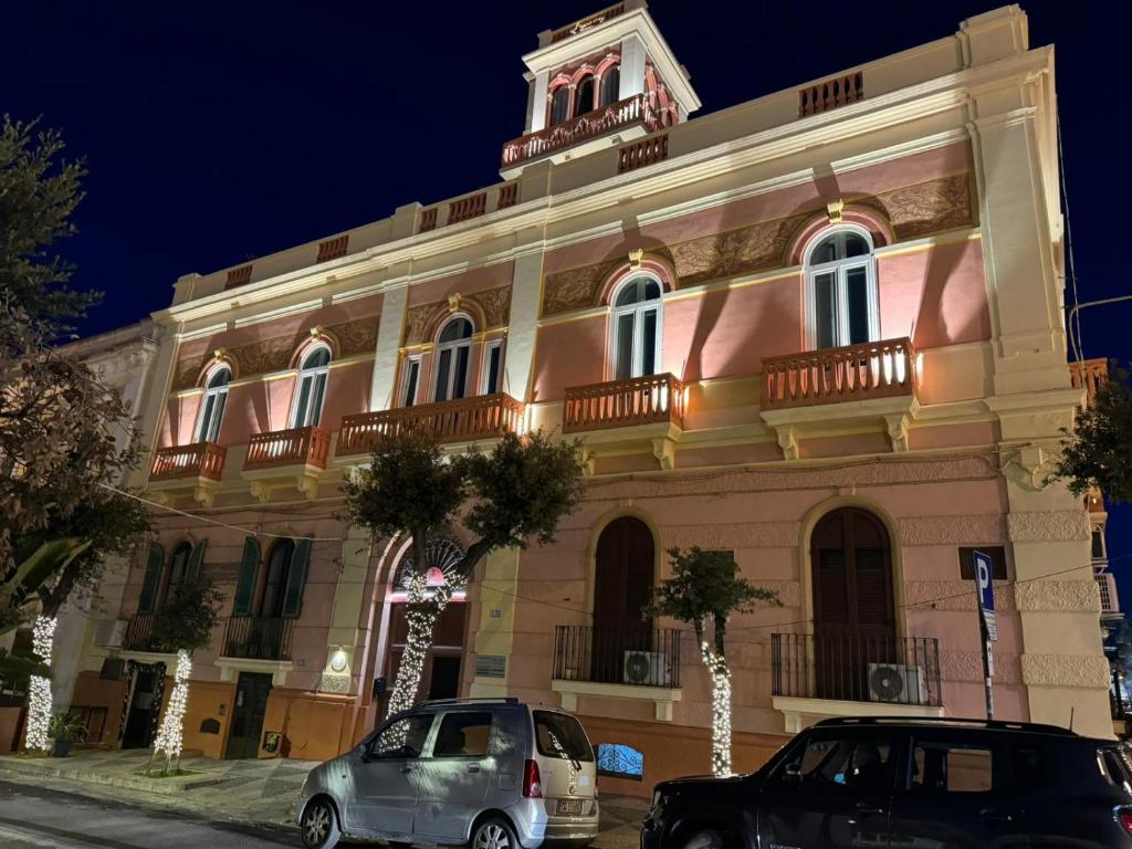 a building with two cars parked in front of it at Palazzo Vallebona in Gallipoli
