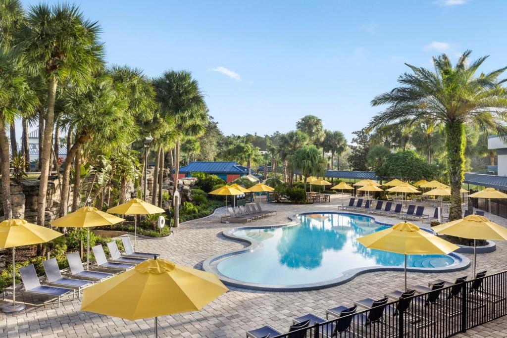 uma imagem de uma piscina num resort com guarda-sóis amarelos em Delta Hotels by Marriott Orlando Celebration em Orlando