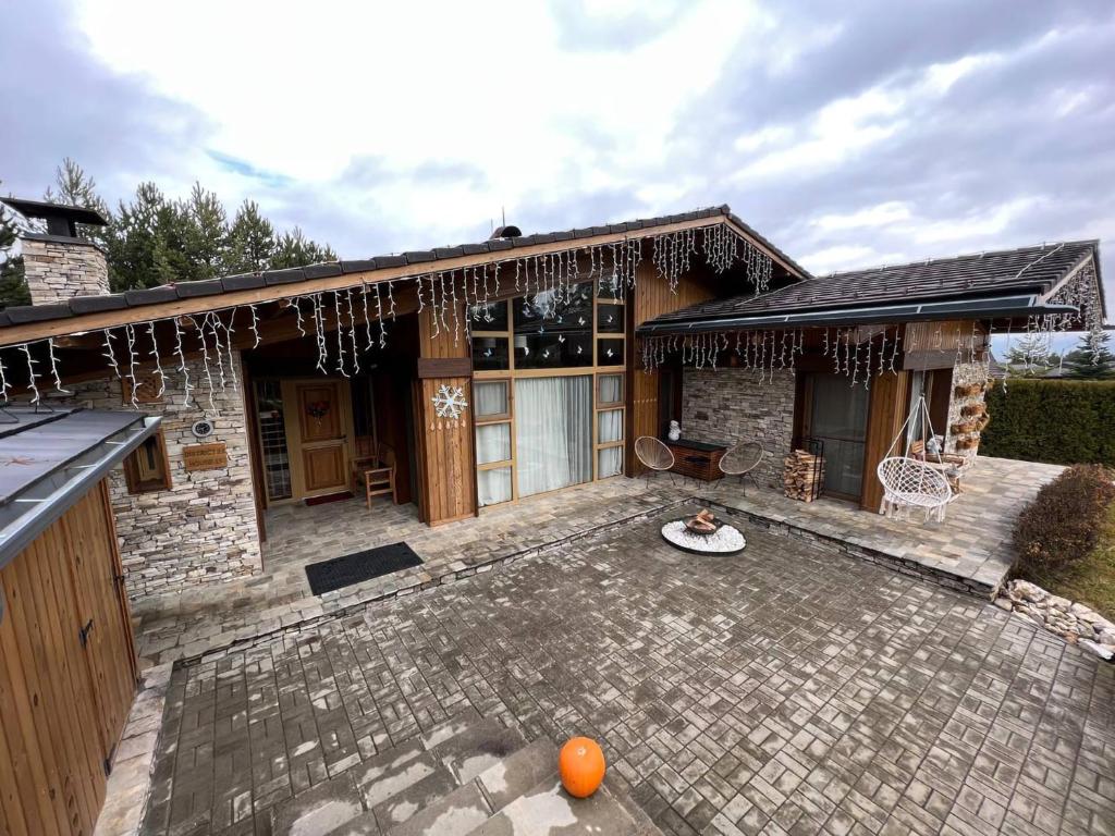 a house with a stone patio with a table at Villa - VALL DI VALL in Pirin Golf & Country Club in Razlog